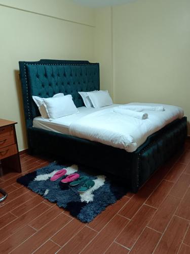 a bed with a black frame and two shoes on a rug at Luxurious 2bedroom furnished apartment in Nairobi