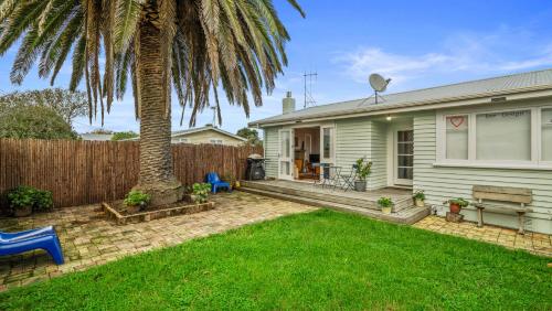 a house with a palm tree in the yard at The Remodelling Room - Mount Maunganui Cottage in Matapihi