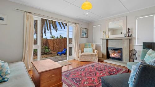 a living room with a couch and a fireplace at The Remodelling Room - Mount Maunganui Cottage in Matapihi