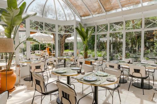 a restaurant with tables and chairs in a conservatory at La Bastide de Saint Tropez in Saint-Tropez