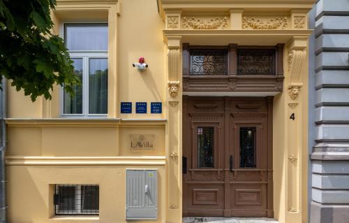 um edifício amarelo com uma porta castanha e janelas em LAVilla Osijek em Osijek