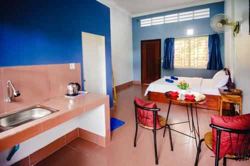 a kitchen with a sink and a table in a room at Lea's Guesthouse and Restaurant in Phumĭ Phlov Phnum Pénh