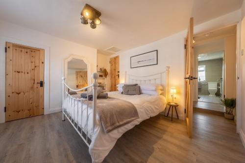 a bedroom with a white bed and a bathroom at Eden Cottage in Wells next the Sea