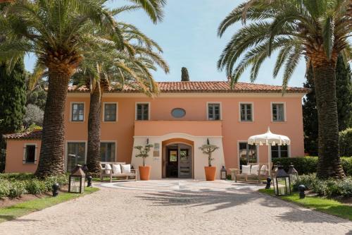 an exterior view of a pink house with palm trees at La Bastide de Saint Tropez in Saint-Tropez