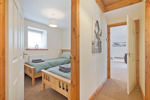 a bedroom with two beds and a door to a hallway at Plum Cottage in Knaresborough