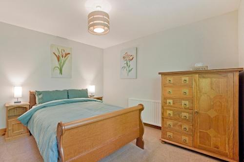 a bedroom with a wooden bed and a dresser at Port Arthur Cottage in Knaresborough