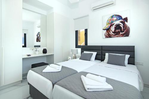 ein Schlafzimmer mit 2 Betten und ein Gemälde eines Hundes in der Unterkunft Villa Mey in Protaras