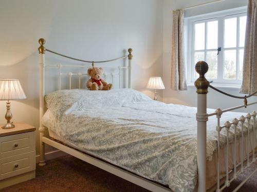 a teddy bear sitting on a bed in a bedroom at Gelli Hir in Bronant