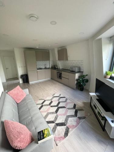 a living room with a couch and a kitchen at Modern Suite- Bedford City centre with free gym & parking in Bedford