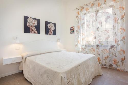 ein weißes Schlafzimmer mit einem Bett und einem Fenster in der Unterkunft Villa Chiara APT 1- Appartamento in villa con piscina in Cavaion Veronese