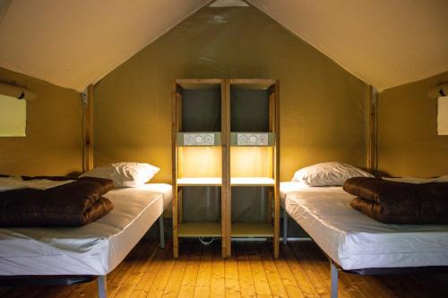 Una habitación con 2 camas en una tienda en Camping Parc d'Audinac Les Bains, en Saint-Girons