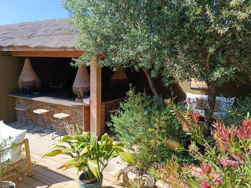 a house with a patio with chairs and trees at Hôtel Les Suites Du Maquis in Bonifacio