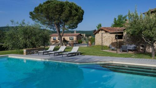 - une piscine avec des chaises et une maison dans l'établissement La Pagliera di Badia a Passignano, à Badia A Passignano