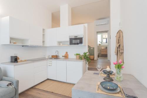 a kitchen and living room with white cabinets and a table at A Step from the Dome Apartment by Rent All Como in Como