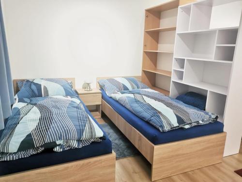 a bedroom with two beds and shelves at Comenius Apartments - Apartmány na rohu in Svidník