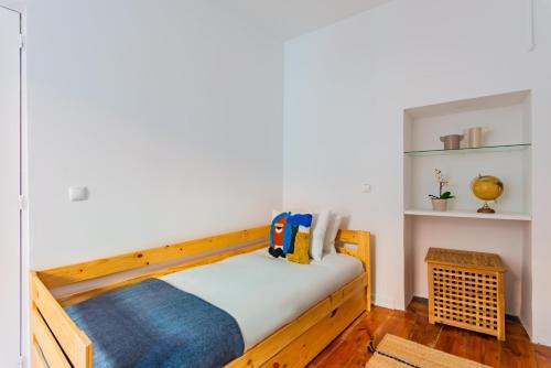 リスボンにあるCasa de Santanaの白い壁の木製ベッド1台が備わるベッドルーム1室が備わります。