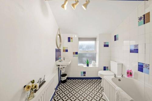 ein weißes Badezimmer mit einer Badewanne und einem Waschbecken in der Unterkunft Aesthetic Cambridge Cottage sleeps 5! in Cambridge