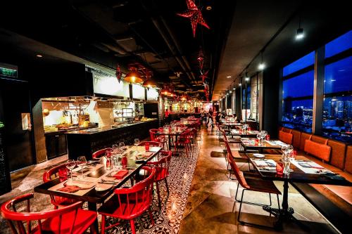 a dining room with tables and red chairs and a bar at Pullman Saigon Centre in Ho Chi Minh City