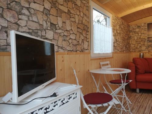 ein Wohnzimmer mit einem großen TV und einem Tisch mit Stühlen in der Unterkunft Schäferwagen Rotkelchen in Ratingen