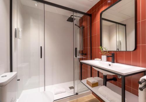 La salle de bains est pourvue d'une douche, d'un lavabo et d'un miroir. dans l'établissement Arrivo Apartments, à Barcelone