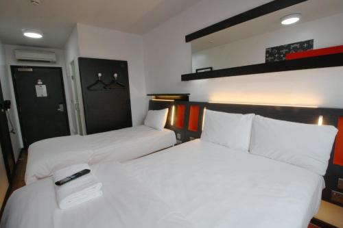 two beds in a room with white sheets and a remote control at easyHotel Newcastle in Newcastle upon Tyne