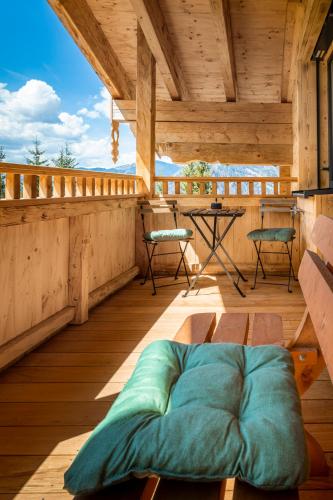 a bed on a wooden balcony with a table and chairs at Taurachhof Astlehen in Alpendorf
