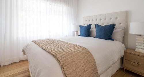 a bedroom with a large white bed with blue pillows at Peninsula Luxury Beach House FREE WI-FI in Rosebud