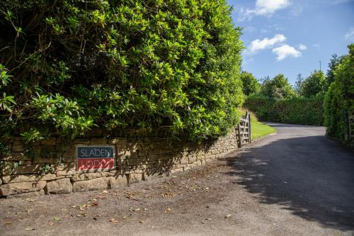 a stone wall with a sign on it next to a road at Sladen Lodge in Hathersage