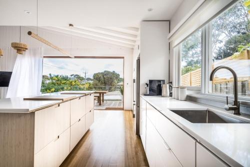 a kitchen with white cabinets and a large window at Peninsula Luxury Beach House FREE WI-FI in Rosebud