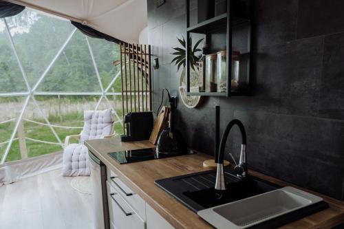 a kitchen with a sink and a counter with a window at GlampingSantoczno in Santoczno