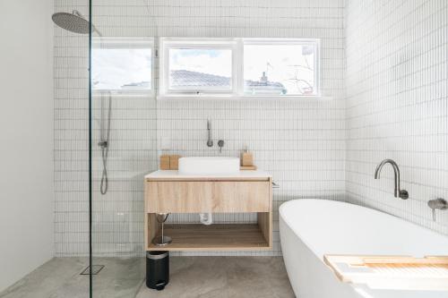 a white bathroom with a tub and a sink at Peninsula Luxury Beach House FREE WI-FI in Rosebud