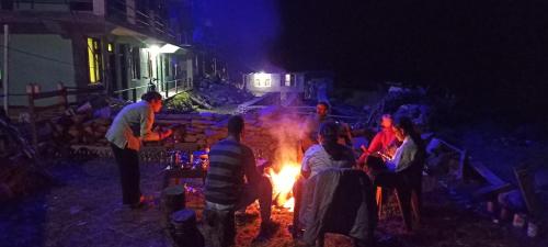 um grupo de pessoas sentadas à volta de uma fogueira à noite em Alpine Homestay at Gadagusain em Banjār