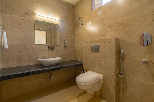a bathroom with a toilet and a sink and a mirror at The Social Stays Manali formerly ArtBuzz in Manāli