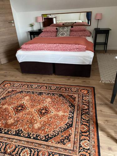 a bedroom with a bed with a rug on the floor at Helga Vendégház in Budaörs