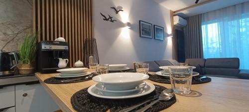 a table with plates and bowls on top of it at Apartament Skorpion Marina & Spa Sagaris Dziwnów in Dziwnów