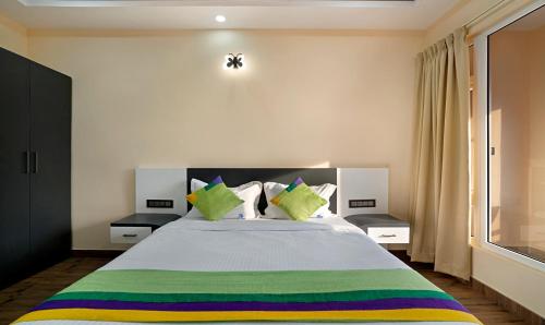 a bedroom with a large bed with green and colorful pillows at Treebo 3C Comforts in Chikmagalūr