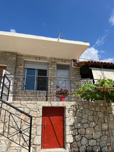 a house with a red door and a balcony at KAFUL APARTMENTS in Qeparo