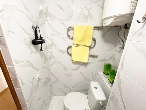 La salle de bains est pourvue de toilettes et d'une serviette jaune. dans l'établissement ARTAL Apartment Yordanska Street 22, à Kiev