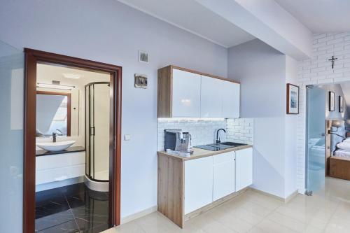 uma cozinha com armários brancos e um lavatório em Avangard by Baltic Home em Świnoujście