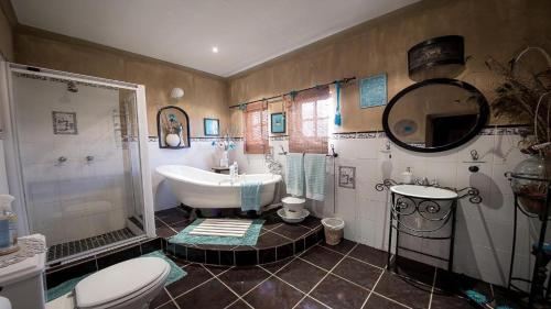 ein Badezimmer mit einer Badewanne, einem Waschbecken und einem WC in der Unterkunft Tarentaalrand Guesthouse in Upington