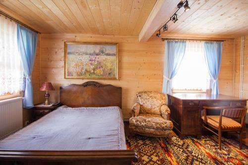 a bedroom with a bed and a desk and a chair at Holiday House Folwark Jeleń in Poniklica