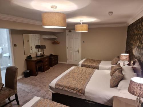 a hotel room with two beds and a desk at Abbey Hotel Donegal in Donegal