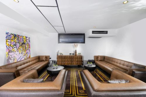 una sala de espera con sofás de cuero y TV de pantalla plana. en מלון בוטיק H34, en Nahariyya