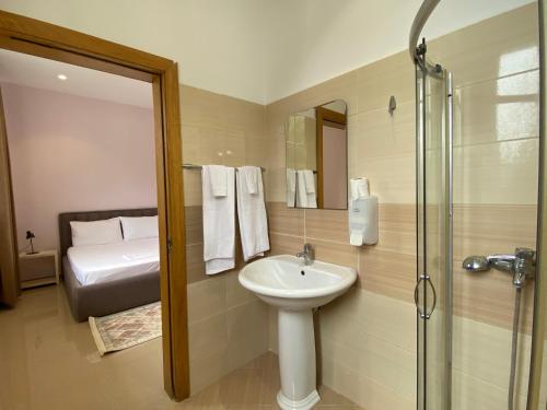 1 cama y baño con lavabo y ducha. en Guesthouse Niko, en Berat