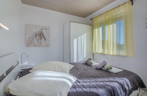 a bedroom with a bed with pillows and a window at Holiday home Nika in Linardići