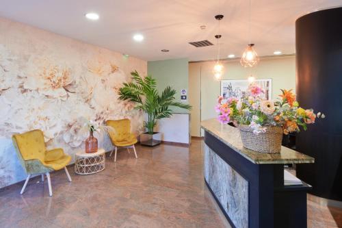 a lobby with yellow chairs and flowers on a wall at Ramblas Vendrell in El Vendrell