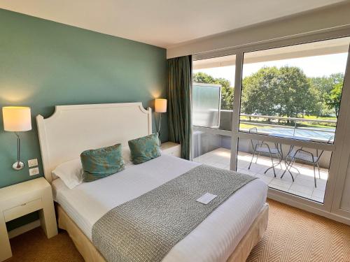 a hotel room with a bed and a balcony at Best Western Plus Le Roi Arthur Hôtel & Spa in Ploërmel