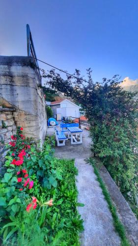 a garden with a picnic table and red flowers at Apartmani Cupic in Budva