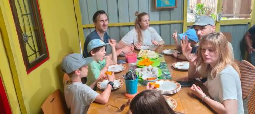 un grupo de personas sentadas alrededor de una mesa comiendo en Ruteng Hostel en Ruteng