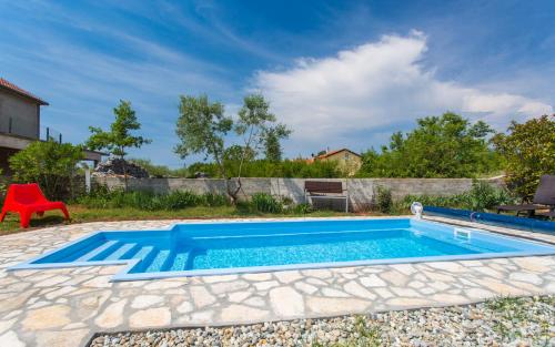 a swimming pool in a yard with a red chair at Holiday home Nika in Linardići